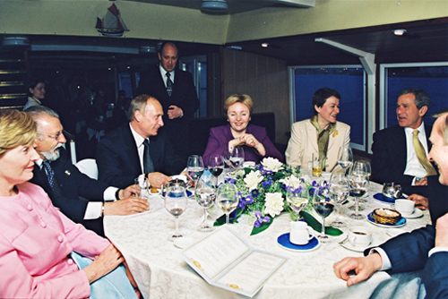 Prigozhin (back) serving Vladimir Putin and George W. Bush on the New Island restaurant boat. // Photo Credit: Wikimedia Commons