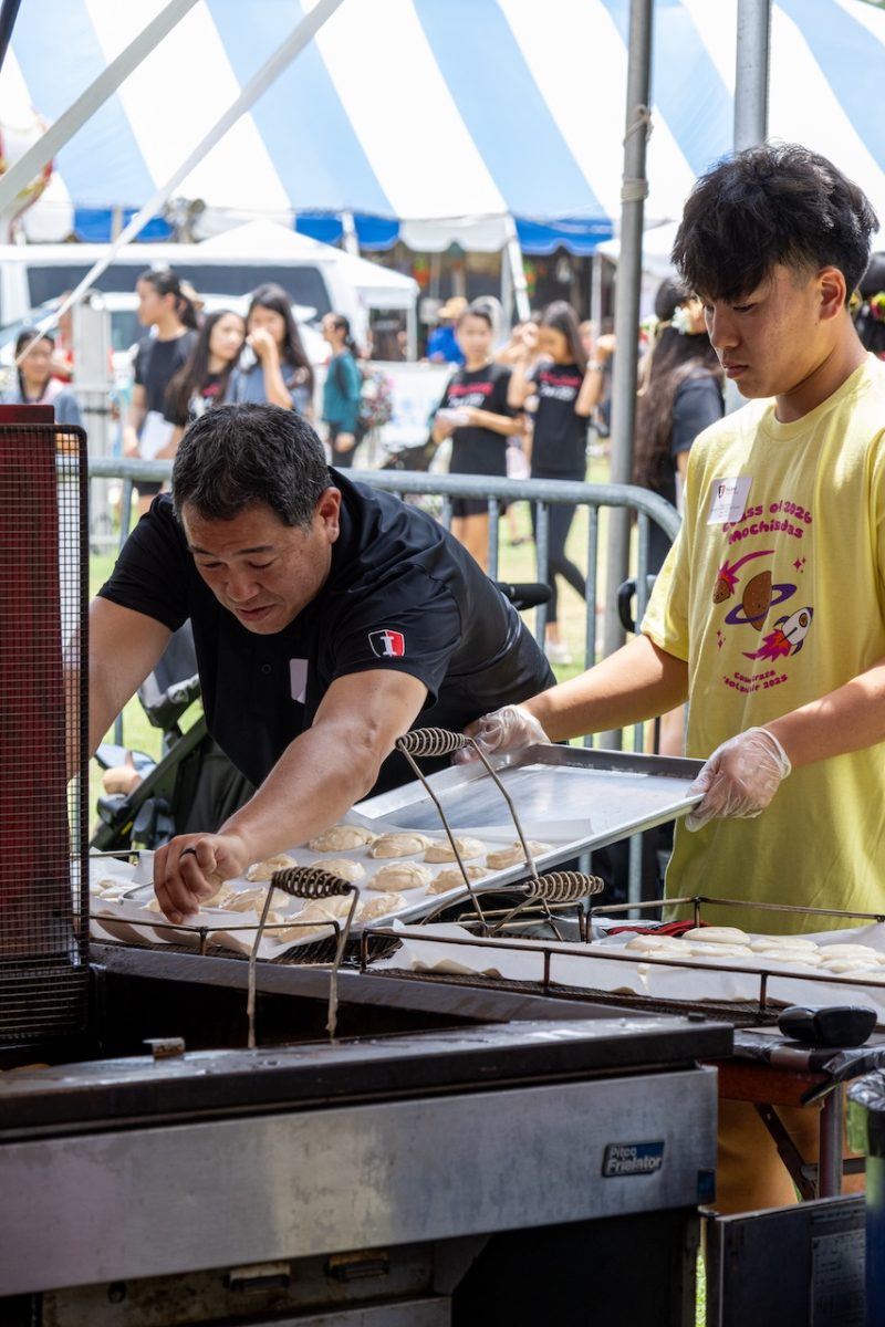 A parent helps a junior lay the mochisada batter onto the frying sheet.
