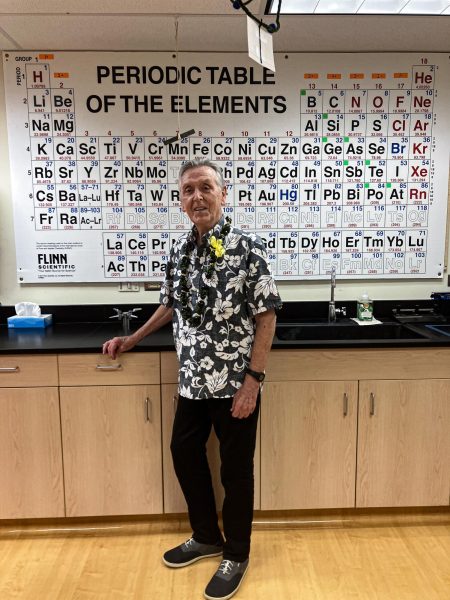 Mr. Heimerdinger strikes a pose in front of the periodic table in his classroom, C-206.