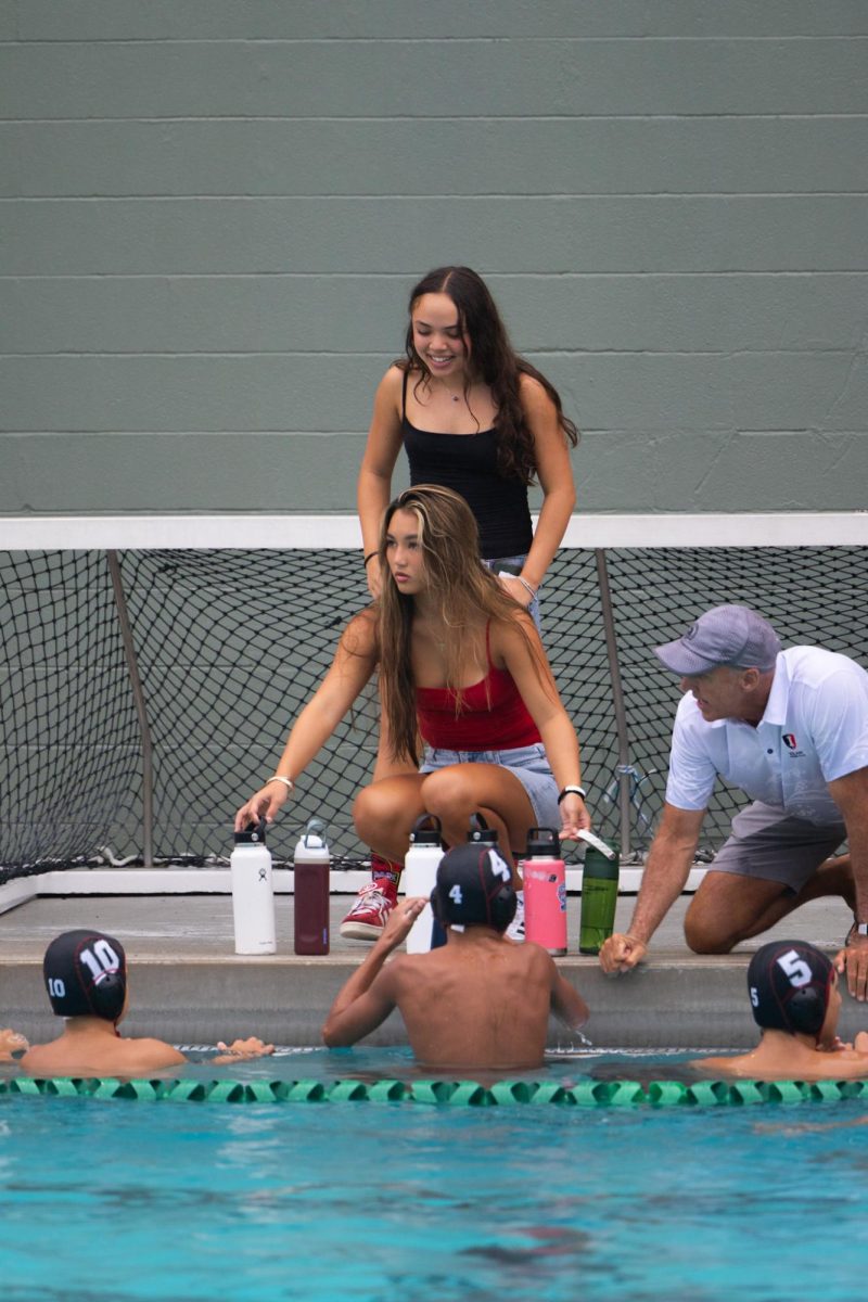 Keani I. ’28 and Zoe O. ’28, team managers of Boys Varsity Water Polo, distribute players’ water bottles